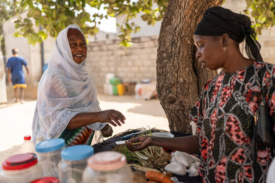 Two women exchanging money at a fruit and vegetable market stall