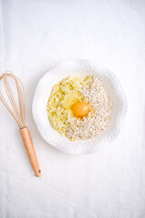 Grated zucchini, egg, oatmeal for pancake for healthy breakfast on white background top view.