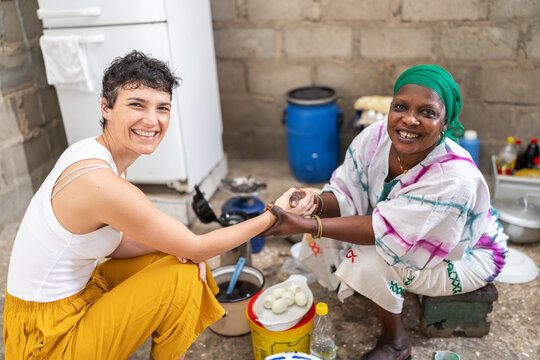 Happy caucasian ngo volunteer holding hands with senegalese woman
