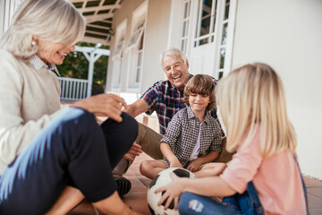 Grandparents and grandchildren having fun on home porch with football