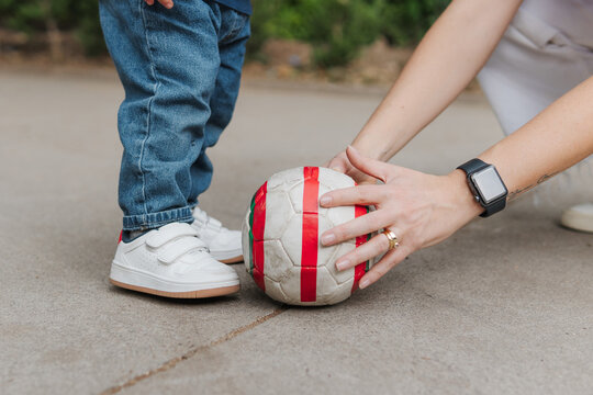 Mom and son playing soccer in the park.