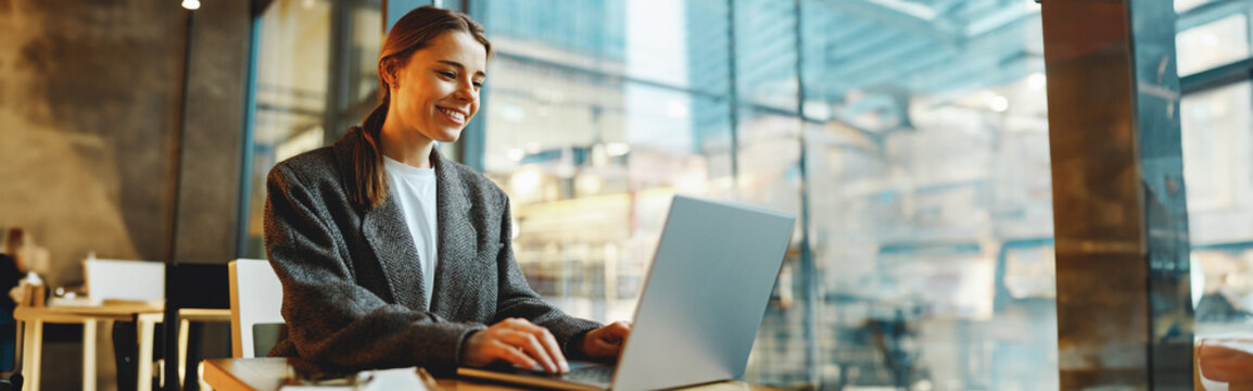 Stylish young female freelancer working on laptop while sitting in cozy cafe