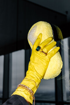 Hand in yellow glove cleaning glass 