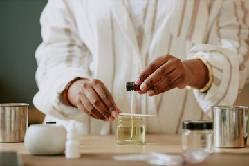 Pair of hands blending essential oils for perfume making in an artisan lab with various containers....