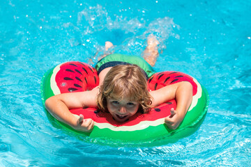 Child swim in summer pool water. Happy kid playing with colorful swim ring in swimming pool on summer day. Child water vacation. Children play in tropical resort.