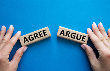 Agree or Argue symbol. Concept word Agree or Argue on wooden blocks. Businessman hand. Beautiful blue background. Gender and Agree or Argue concept. Copy space