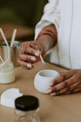 Person meticulously blending skincare ingredients, using a small mixing bowl, creating handcrafted natural beauty products in a serene workspace, showcasing delicate manual work with attention