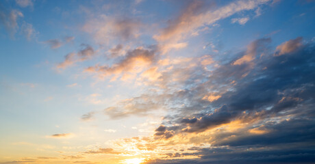 Fototapeta premium Sunset or sunrise. Dramatic majestic scenery sunset. Sky with clouds in sunset sky light background. Sunrise with clouds in various shapes. Calm sunset sky and sun through clouds over.