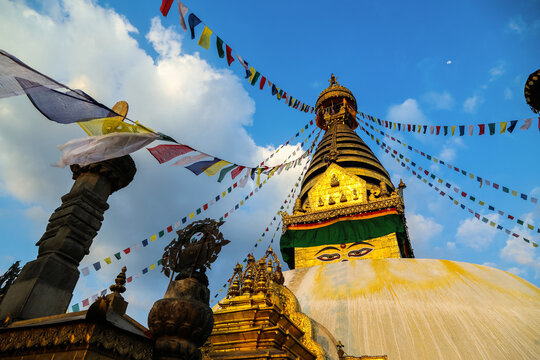 Golden Swayambhunath stupa with prayer flags at sunset