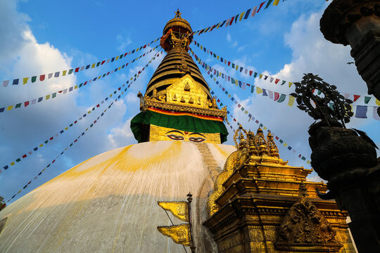 Golden Swayambhunath stupa with prayer flags at sunset