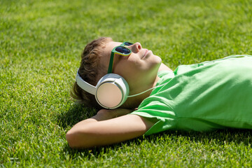 Naklejka premium A boy relaxing on grass, listening to music