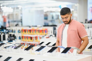 Indian man customer buyer at mobile phone store choose his new smartphone