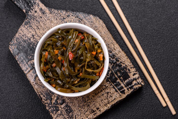 Delicious marinated seaweed with paprika, spices and salt on a dark concrete background