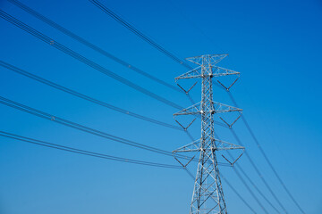 Electric pole with wires against a blue sky, showing power lines in close up.