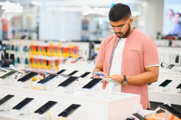 guy in an electronics store chooses a cell phone to buy