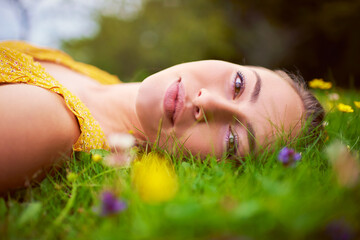 Woman, portrait and relax on grass outdoor, travel and countryside nature for peace or calm. Female person, rest and field or meadow for wellness, spring garden and flowers in park on holiday trip