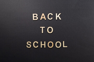 Wooden letters on black background. caption "Back to School." Top view. For backgrounds and presentations