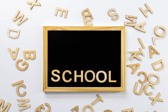 Black school blackboard with "School" inscription in wooden letters. Scattered letters side by side. Top view. For backgrounds and presentations