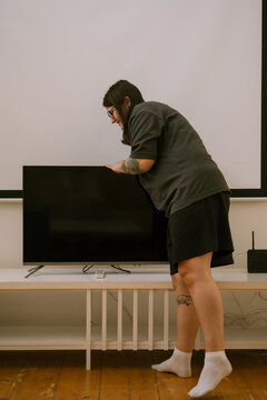 Woman setting flat screen television on TV stand cabinet