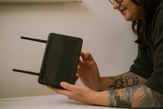 Woman kneeling and fixing Wi Fi router