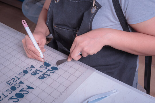 Young woman removes excess material with weeding tool, cutting plotter workplace.