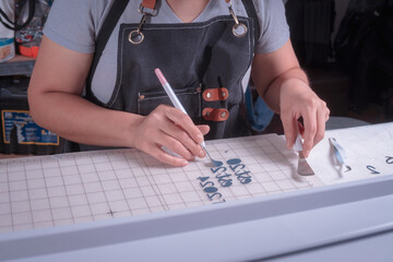Young woman removes excess material with weeding tool, cutting plotter workplace.