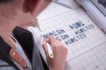Young woman removes excess material with weeding tool, cutting plotter workplace.