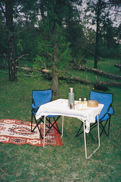 Portable table and camping chairs set at campsite with drinks