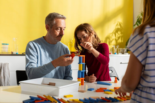dad and daughters playing with dominoes