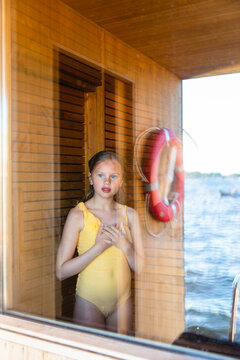 A girl looks out at the fjord from a sauna in Oslo
