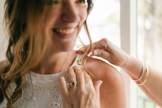 hands of grandmother fixing pin/brooch on bride's dress