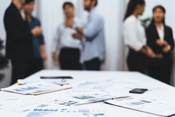 Business intelligence and analyzed financial data visualized on papers with blur background of analyst team utilizing BI Fintech in meeting room for business insight and marketing planning. Prudent