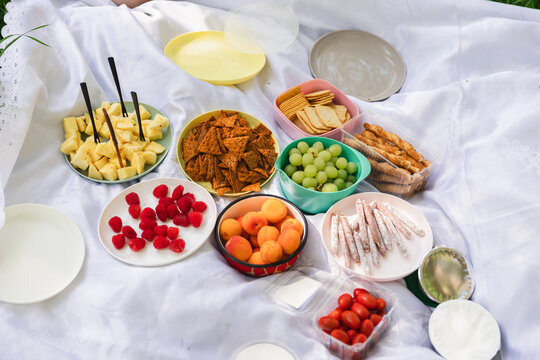 Summer Picnic with Fruits and Snacks on a White Blanket