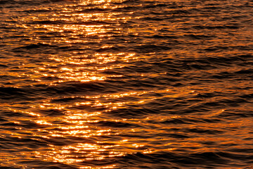 Sunlight sparkles over ocean waves. Liquid golden splash texture.