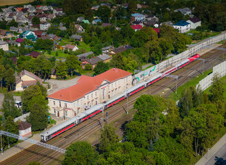 Obraz premium Railroad station in Kaisiadorys, Lithuania. Aerial drone view photo of passenger and freight train station with train passing by