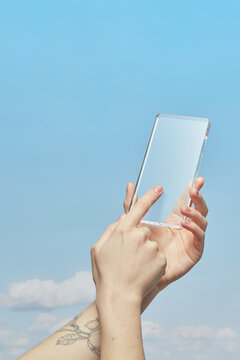 Female using touchscreen of modern telephone over sky with clouds