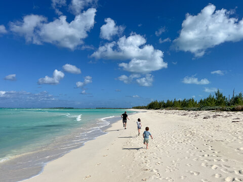 Family runs together down beautiful beach in Green Turtle Cay, Bahamas