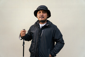 Photo of Asian man wearing all black adventure outfit. Half body portrait of an adult adventurer...