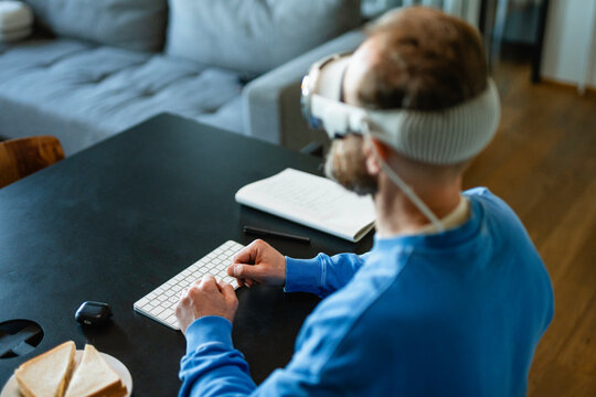 A man in a virtual reality headset typing on the keyboard