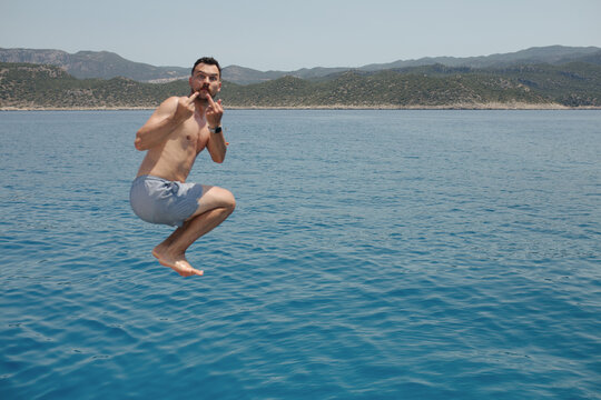 Men jumping in the sea and showing middle finger