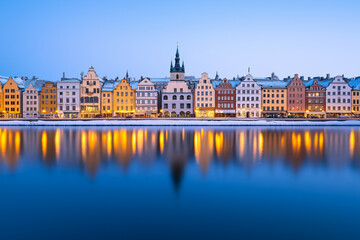 Fototapeta premium Scenic winter evening view of colorful old town buildings reflecting in calm water in Stockholm, Sweden, perfect for Christmas cards