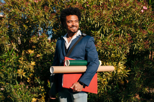 Professional man holding folders and portfolio tubes