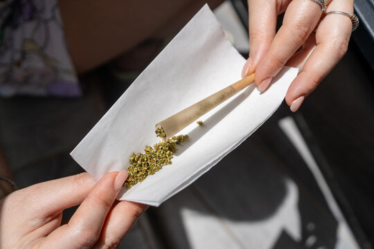 Young Woman Rolling Cannabis Joint Outdoors