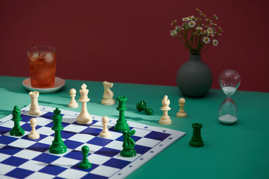 Chessboard with Pieces, Hourglass, and Iced Tea on Green Table