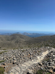 Beautiful panoramic view from Psiloritis (summit Ida), Mount Ida in Kouloukonas, Crete, Greece. Hiking in the sun, rocky terrain with clear blue sky.