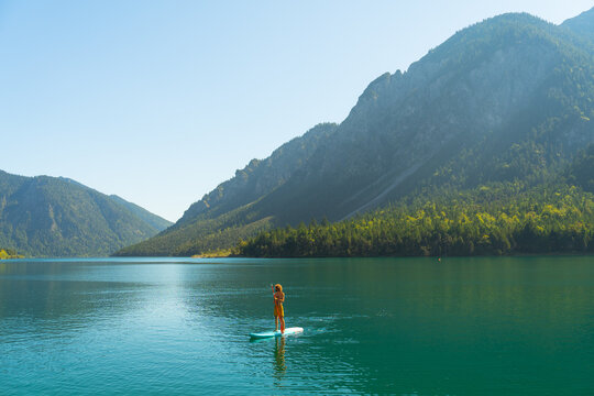 Man SUP boarding on turquoise lake in Alps 
