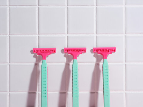Three razors arranged in a row against a white tiled background