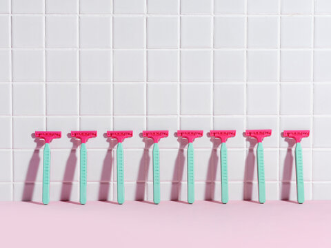 Seven Pink and Teal Razors on Tiled White Background