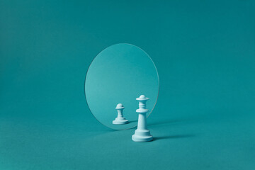 White chess queen against mirror with reflection of pawn