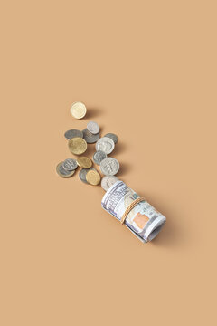 Roll of money fixed in tube laying next to handful of coins